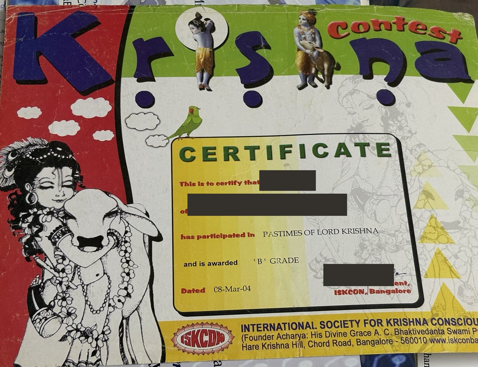 Colourful Krishna contest certificate awarding a B grade, with the name, school and signature blocked out.